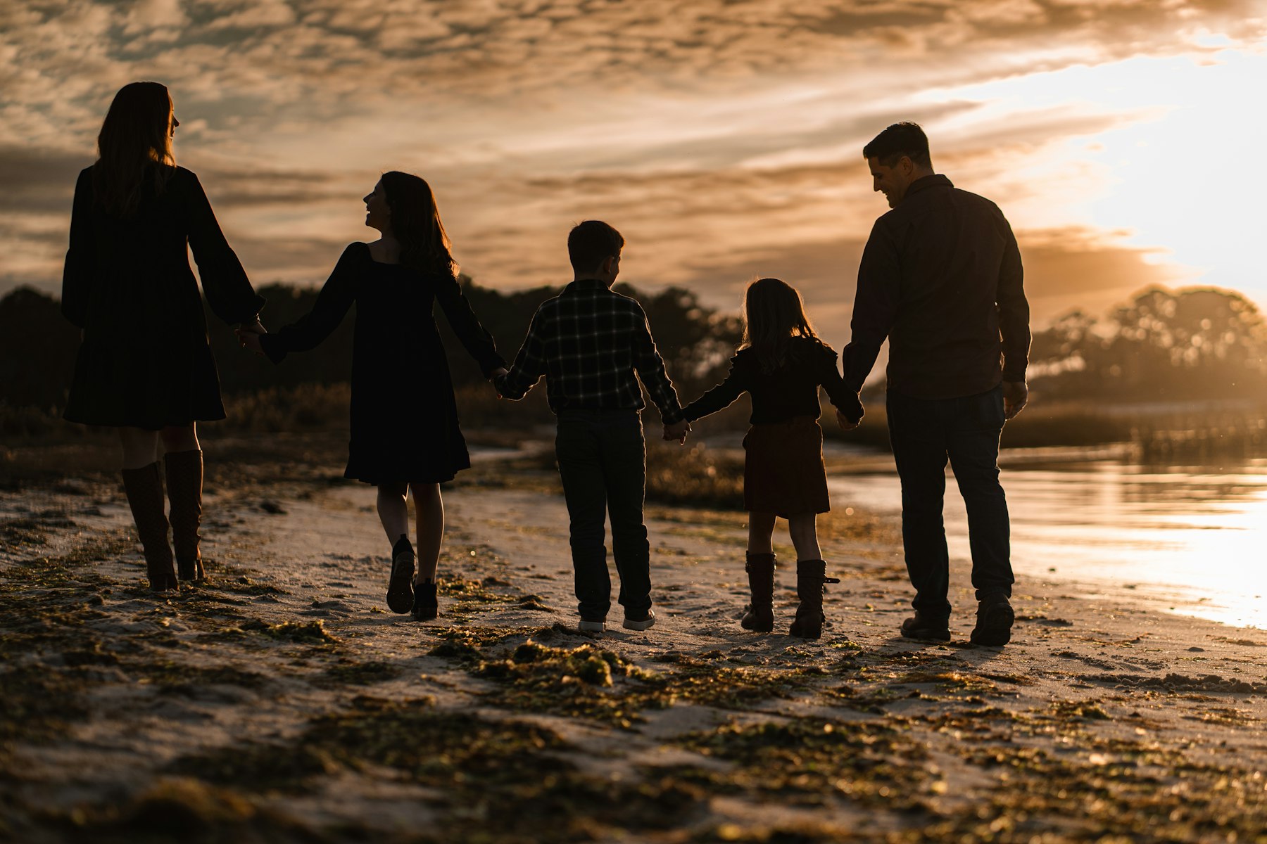A family of five walking the beach at sunset