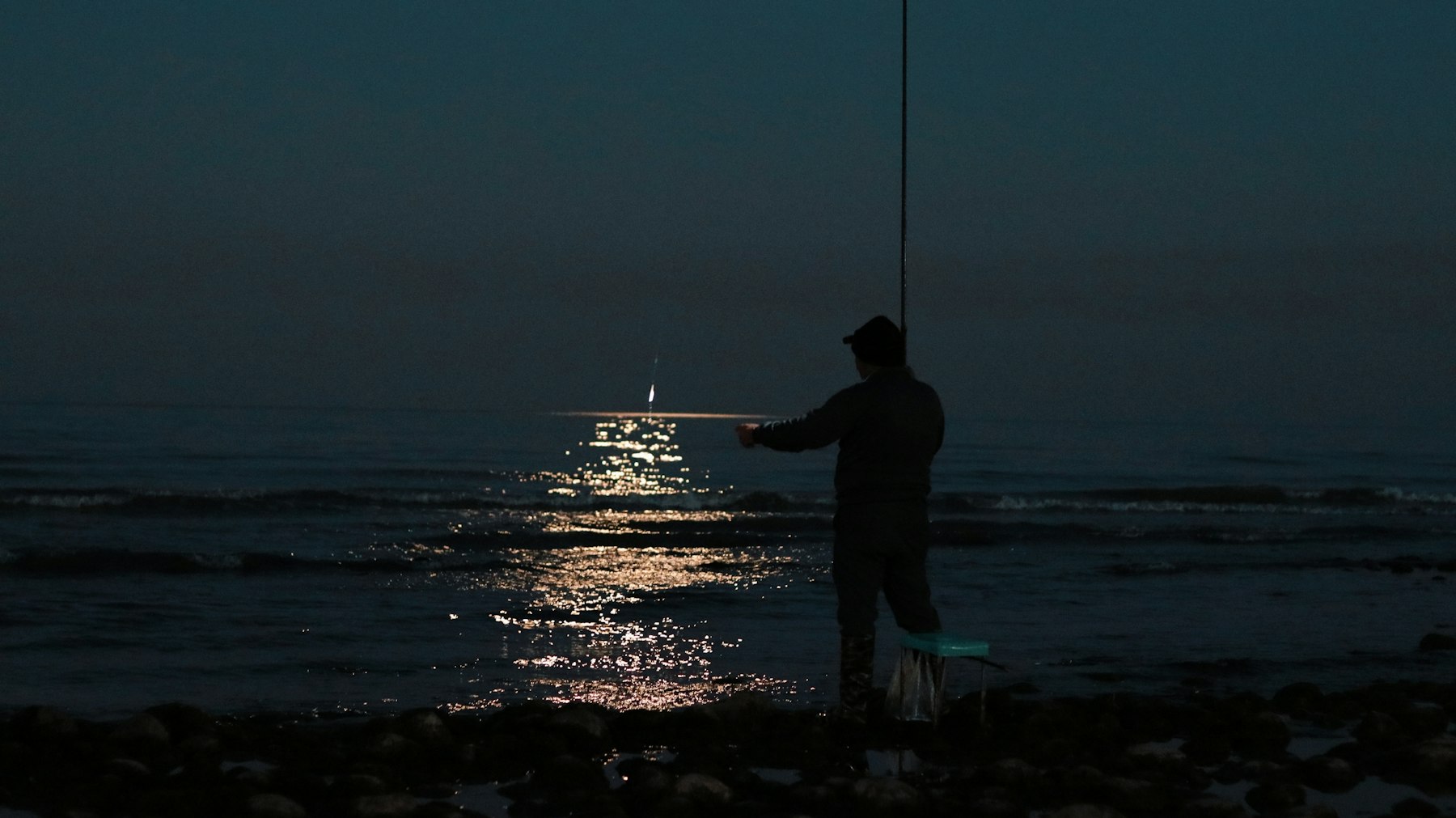 An angler fishing the Gulf surf at night
